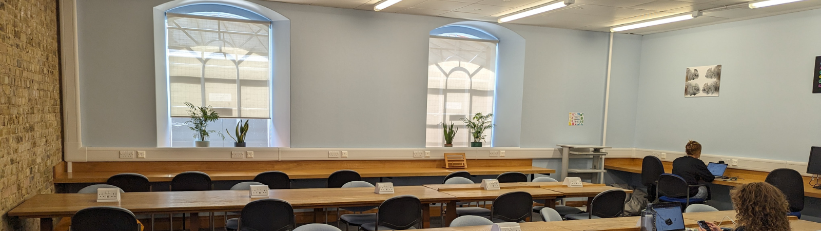 A landscape shot of the PDN Library's Quiet Space with rows of wooden desks, all with power points, and lots of comfy seating. It is a light and airy space. 